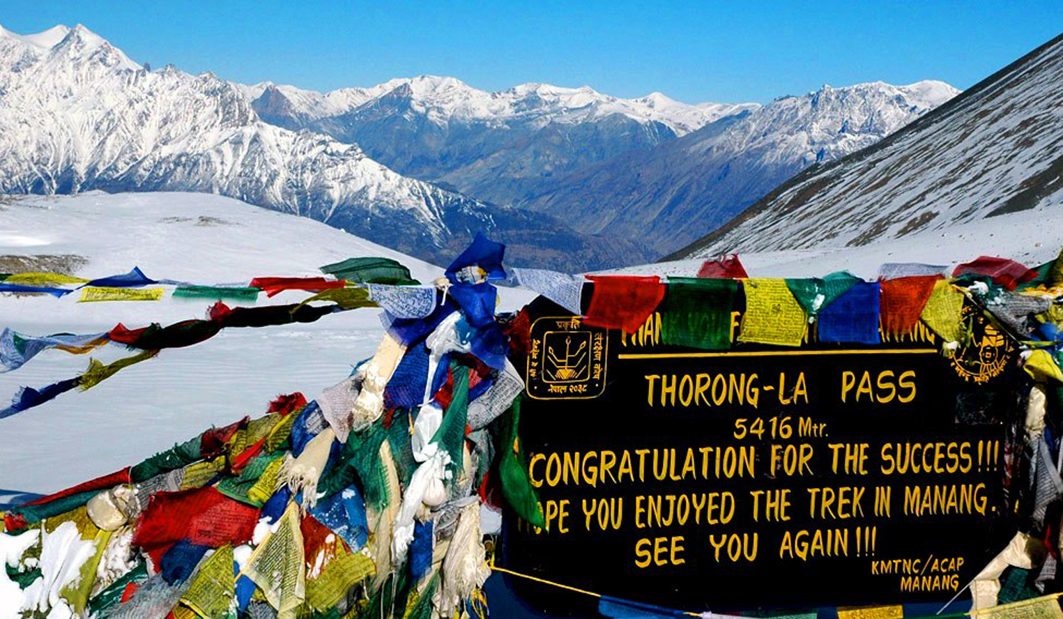 Trekkers crossing Thorong La Pass at 5,416 meters on the Annapurna Circuit Trek, surrounded by snow-capped Himalayan peaks.